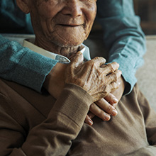 A nurse with their hands around a seated patient